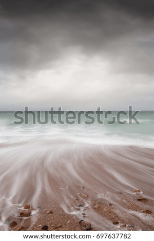 Beach waves pebbles cloudy sky