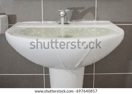 Overflowing water from the washbasin Royalty-Free Stock Photo #697640857