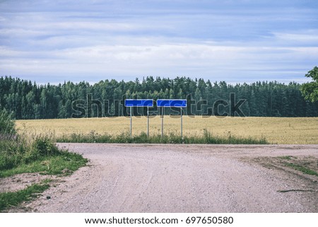 romantic gravel road in country under blue sky and white clouds - vintage film effect