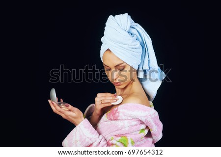 Young beautiful woman with towel on head nourishes the skin on a dark background. Beauty treatments .