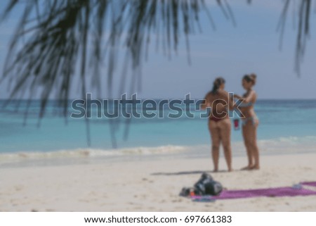The blurred image of unidentified two woman in bikini having activities on the beach.
