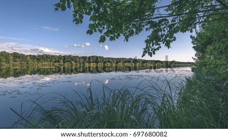reflection of clouds in the lake with forest  and trees in background and horizon line - vintage film effect