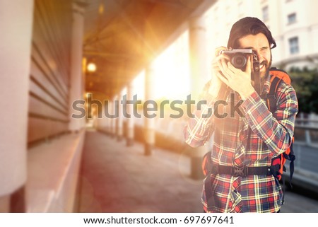 Hiker taking picture with camera against architectural columns in building