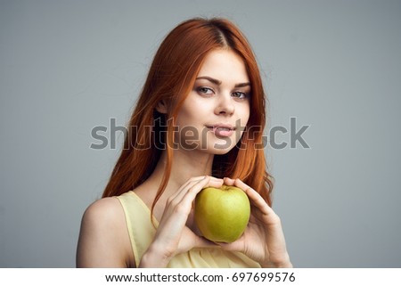 Healthy food, fruit, young woman holding a green apple on a gray background, healthy lifestyle                               