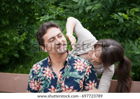 Charming couple of a man and woman sitting on the bench, woman embraces man