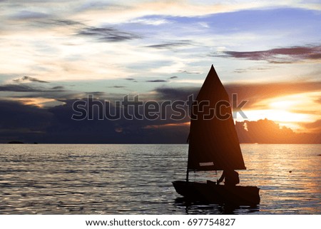 Sunset in the ocean with a man sailing on the ocean with colorful sunset sky and silhouette of sailing. sailboat.People.Clearing day and Good weather in the Evening.Weather in the evening.