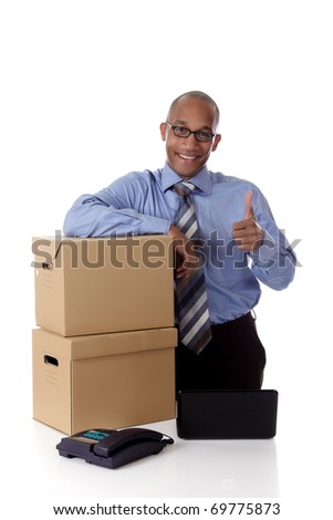 Young attractive African American businessman in office against the postal boxes with the thumb up, laptop and telephone on desk . Studio shot. White background.