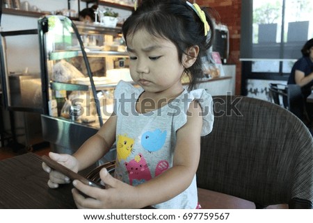 Little asian girl watching cartoon on mobile phone
