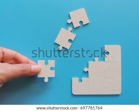 Concept of business,hand holding a puzzle piece on puzzle background.
