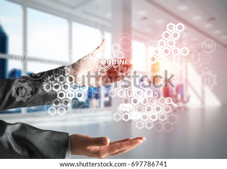 Cropped image of business woman in suit with business interface and media icons in her hands. Sunlight and office view on background. Mixed media.