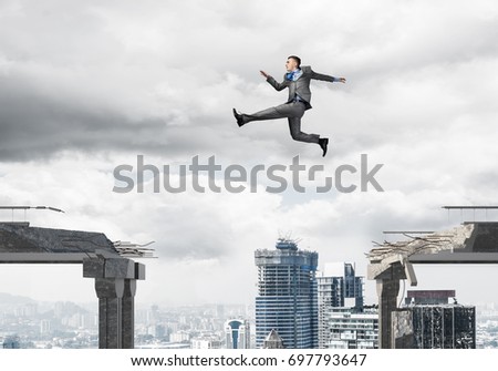 Businessman jumping over gap in concrete bridge as symbol of overcoming challenges. Dark sky and cityscape on background. 3D rendering.