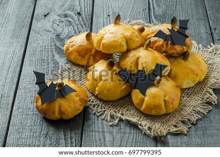 Homemade sweet pumpkin buns. Original baking in form of pumpkin and bats made of paper. Symbols and characters Halloween. Idea of design meal for Halloween party. Scary and funny Halloween food