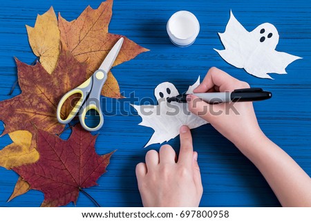 / Making ghosts from maple leaves to Halloween. Halloween decor of room. Children's art project. DIY concept. Step-by-step photo instructions. Step 4. Child draws eyes and mouth of ghost