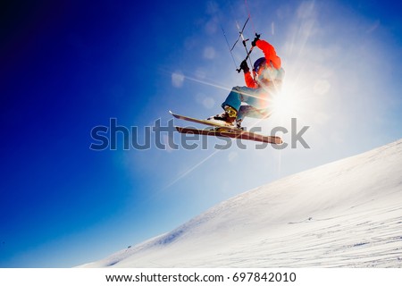  Skier with a kite on fresh snow in the winter in the tundra of Russia against a clear blue sky. Teriberka, Kola Peninsula, Russia. Concept of winter sports snowkite on ski. Royalty-Free Stock Photo #697842010