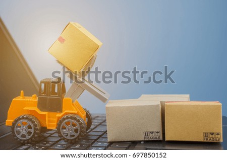 Forklift truck with boxes on a laptop keyboard,on blue wall background.concept online shopping.