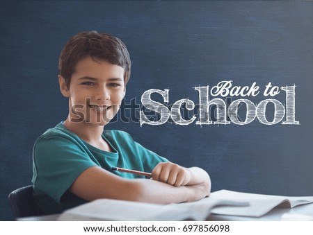Digital composite of Student boy at table against blue blackboard with back to school text