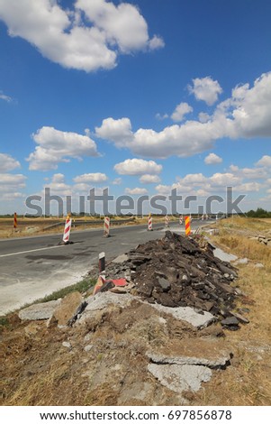 Damaged asphalt road and small bridge in reconstruction with blue sky and clouds