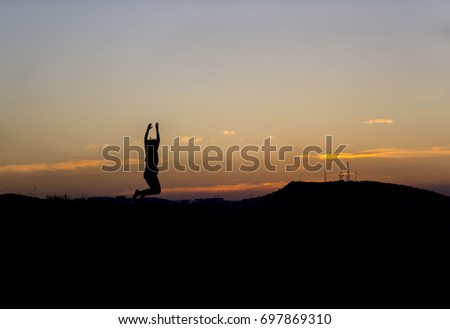 Girl jumping up against a beautiful sunset, the picture shows her silhouette