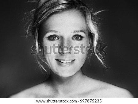 Portrait of Pretty young blonde woman with freckles. Black background