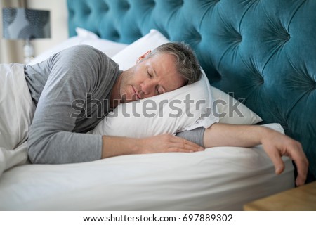 Man sleeping on bed in bedroom at home Royalty-Free Stock Photo #697889302