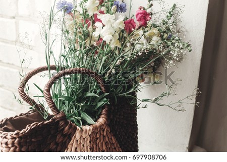 wildflowers in wicker bag on rustic white window. colorful flowers in brown basket in sunlight, space for text. rural atmospheric moment. unusual summer picture