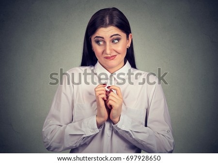 Portrait of a young woman in awkward situation, playing nervously with hands. 