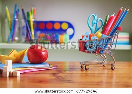 Back to School Shopping Cart with Supplies on Wooden Table. Shopping cart filled with with school necessities. 