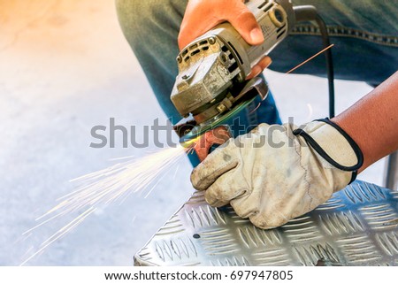 Worker using angle grinder in factory and throwing sparks. Electric grinder metal with worker cutting metal. Angle grinder for safety first with copy space.