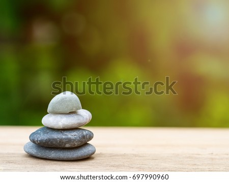 Four stones stacked placed on a wooden board. The backdrop is black on green.