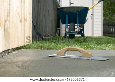 A cement screed resting on a finished concrete slab in backyard, DIY home project themed image. Royalty-Free Stock Photo #698006371