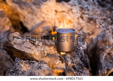A mug near a camping fire on a hike trip