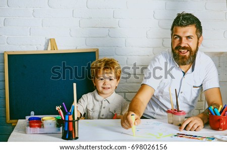 Art for children. Bearded adult father teaches to draw little son in studio. Boy and man draw picture. Creative education and art, development in kindergarten. Childhood with parents talented teacher