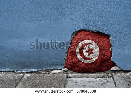 Concept image. Stone in the cement wall with Tunisia flag on it. National country's symbol. Traveling and patriotism theme.