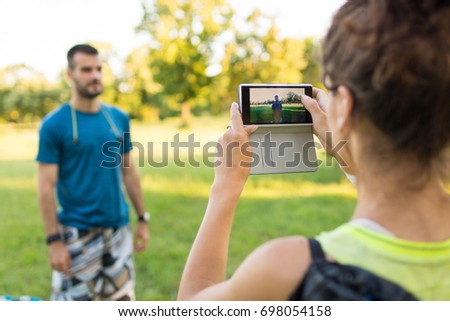 Closeup rear view shot of a young athlete couple taking pictures of each other using smart phone outdoors. Taking a pic!