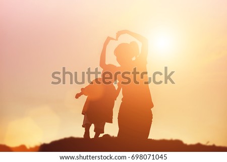 Mother encouraged her daughter out of the shadows at sunset.