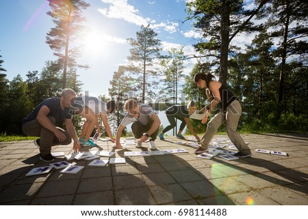 Full Length Of Coworkers Solving Crossword Puzzle In Forest Royalty-Free Stock Photo #698114488