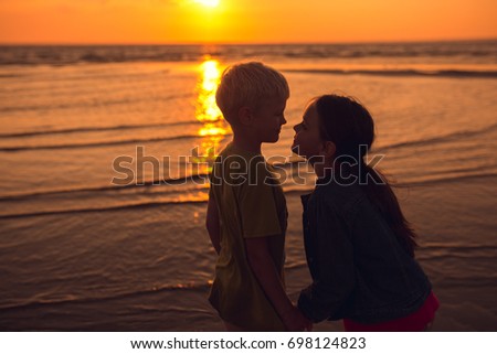 Happy children playing on the beach during sunset. Entertainment in the summer holidays
