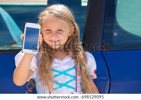 Bla bla car calling taxi app searching concept. Little girl kid child showing at the phone screen standing near a blue car
