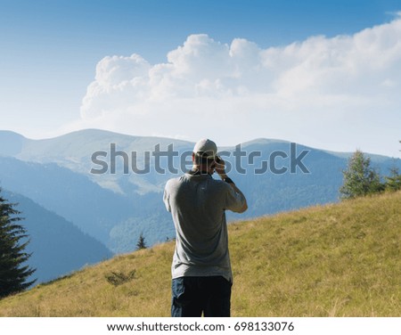 A man with a camera in the background of a mountain landscape