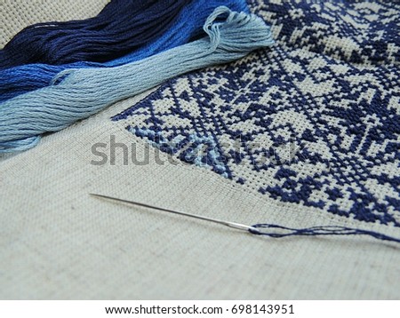 Navy, blue, grey threads and needle for embroidery. Authentic traditional men shirt on background.