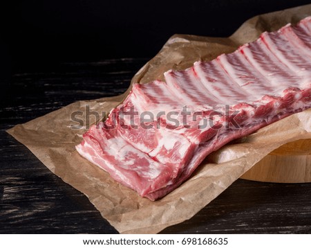 Meat ribs on dark black background in food market.