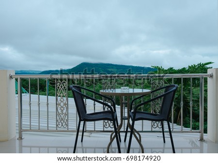 chair and table placed outside the room in morning. scenery mountain are background. this image for home, travel, nature, hotel, resort, exterior concept
