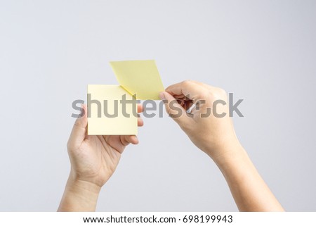 Hand holding sticky post note paper sheet on white background Royalty-Free Stock Photo #698199943
