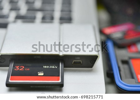 32 GB compact flash memory card in card reader on laptop keyboard background