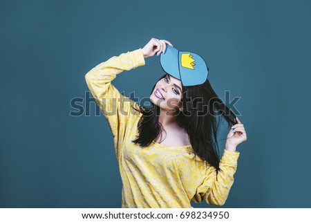 Model woman young and beautiful in the style of pop art on a blue background painted in a cap with a crown