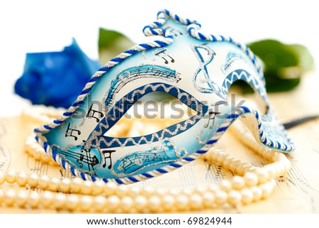 Blue and white carnival mask on a music paper with blue rose on the background