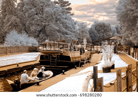 A stylized infrared image of boat queuing at Temple Lock near Marlow. The lock has a brown warmth while the surrounding trees display their infrared tones.