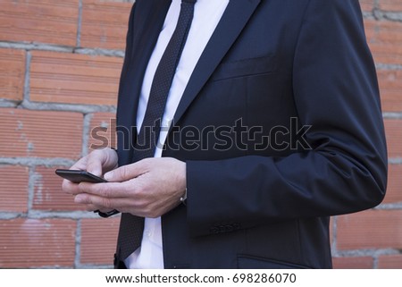 Hands of man with suit using cellphone