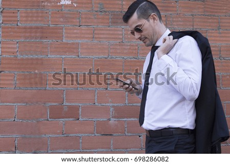 Man in suit and sunglasses on brick background using mobile phone