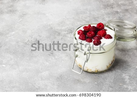 Glanola in glass jar with raspberry on a gray background. Copy space. Food background